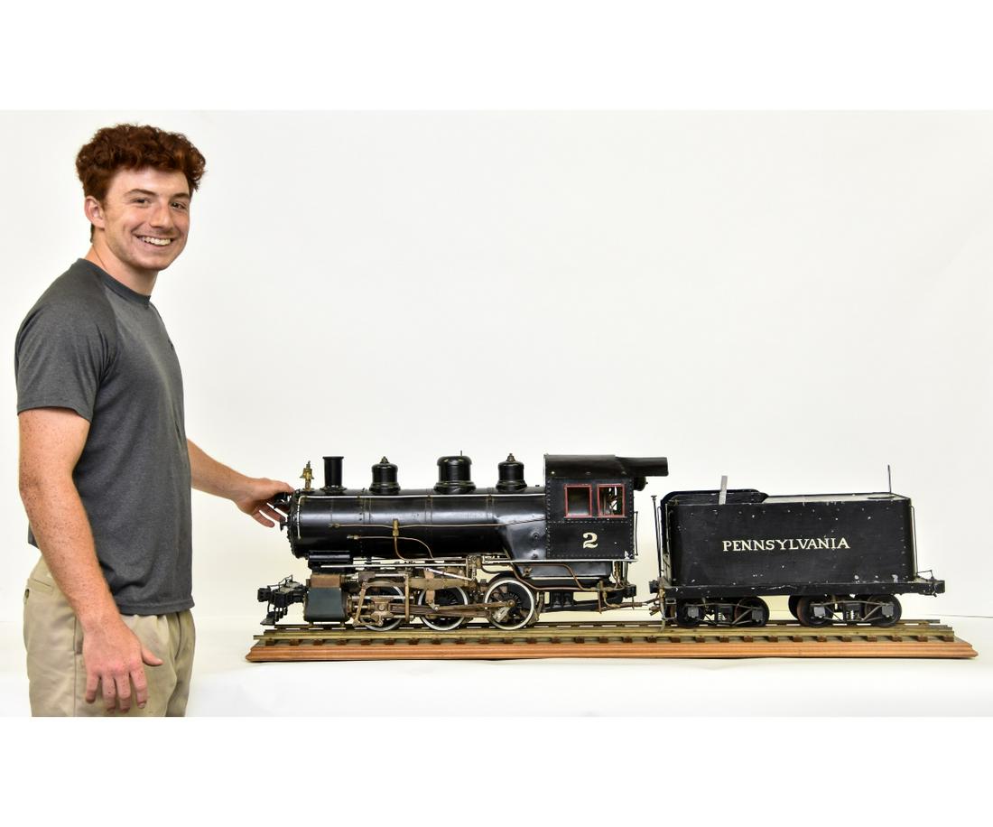 Live Steam Pennsylvania Railroad 0-6-0 Locomotive: Live steam Pennsylvania Railroad 0-6-0 locomotive, circa 1970's, brass/metal, Baldwin Locomotive Works builder plate, 5-gauge, mounted on track 16"h x 35"l x 10.5"d engine / 12"h x 23"l x 10"w tender