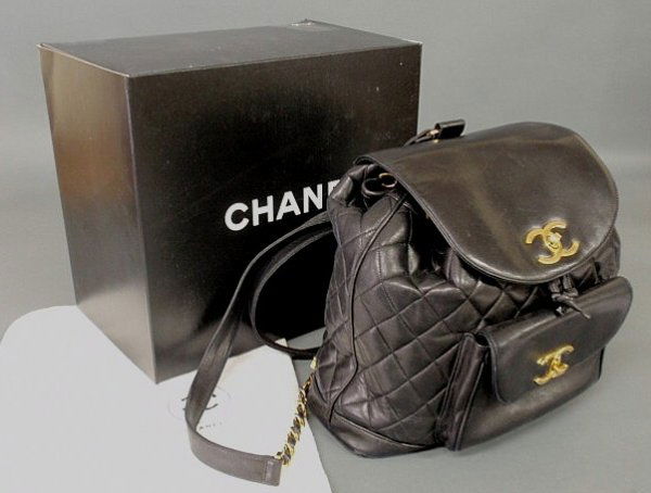 Chanel black quilted leather backpack bag with an: Chanel black quilted leather backpack bag with an inner drawstring close, outer flap and pocket both with gold tone logo closures, gold tone chain and leather strap, dust cover and box, approx. 12"h.x