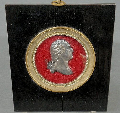 Miniature side portrait of George Washington, prob: Miniature side portrait of George Washington, probably 19th c., in raised relief cast metal and mounted on a round red painted wood field in a black painted wood frame measuring 6.5"x5.5