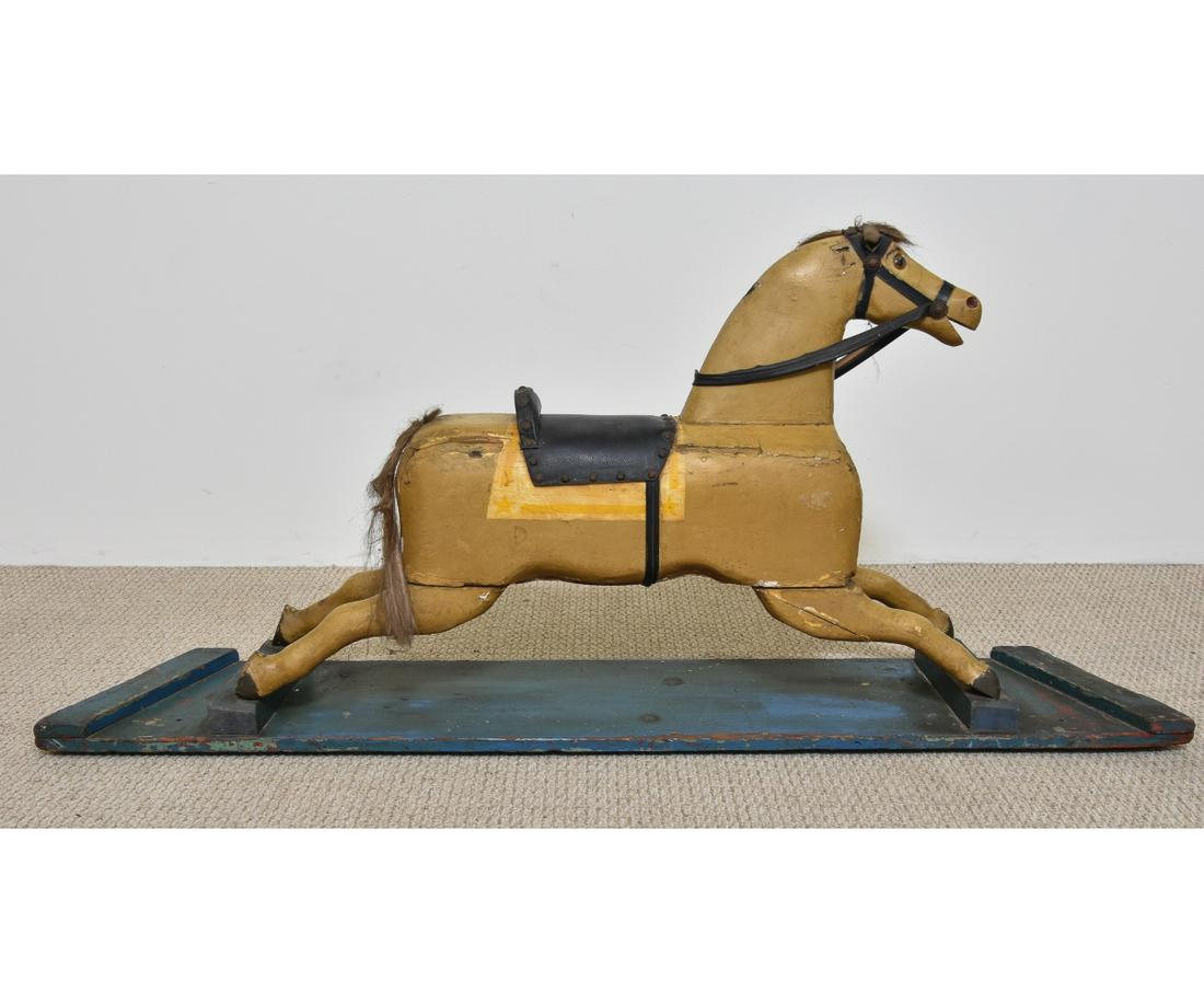 Carved Wood Rocking Horse: Carved wood rocking horse with glass eyes and leather saddle, circa 1900. 26.5"h x 60"l x 11.5"d