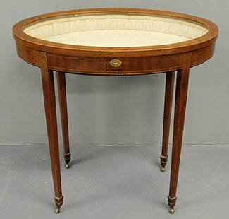 Oval mahogany curio table, late 19th c., with lin: Oval mahogany curio table, late 19th c., with line inlay and metal casters. 29.5"h., top 29.5"x18