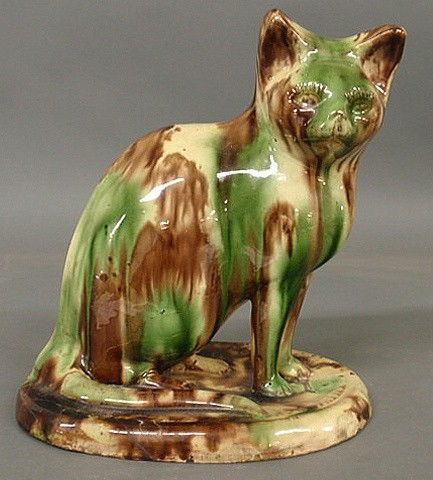 Redware seated cat with mottled green and brown g: Redware seated cat with mottled green and brown glazing, 19th c. As found. 10.5"h.x10"w.