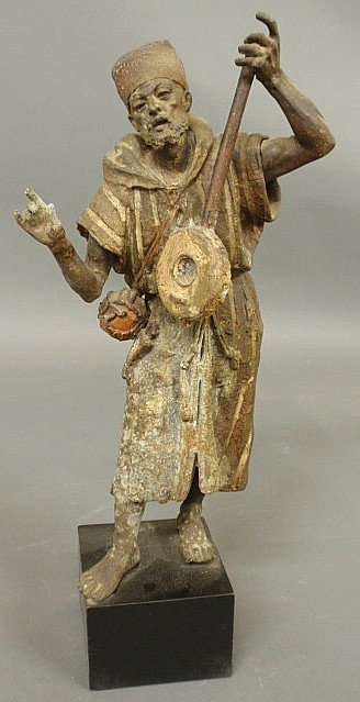 Pot metal statue of a man playing a stringed inst: Pot metal statue of a man playing a stringed instrument, 20th c., and mounted on a wood base. As found. 21.5"h.