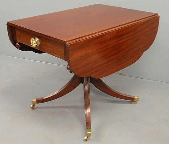 Duncan Phyfe mahogany drop-leaf table with reeded: Duncan Phyfe mahogany drop-leaf table with reeded down-swept legs and brass casters. 29.5”h.x24.5”w.x36”d., leaves 11.75”