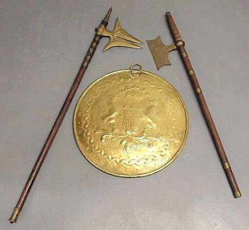 Continental brass plaque decorated with an armoria: Continental brass plaque decorated with an armorial crest 17”dia. and two brass and wood axes (as found) largest 36”l.