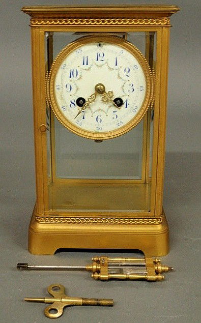 French brass and beveled glass mantel clock with a: French brass and beveled glass mantel clock with a porcelain dial and mercury pendulum. As found. 10”h.x6”w.x5”d.