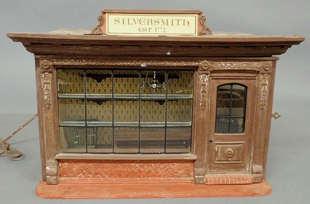 Metal and wood toy Colonial "Silversmith Shop" wi: Metal and wood toy Colonial "Silversmith Shop" with miniature metal pieces of "silverware", electrified. 10"h.x17.5"w.x9.5"d.
