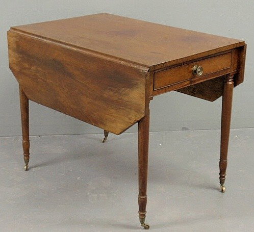 American Sheraton mahogany drop-leaf table, c.182: American Sheraton mahogany drop-leaf table, c.1820, with a single drawer, shaped leaves, turned legs and brass casters. 28.5"h.x25"w.x36"d.