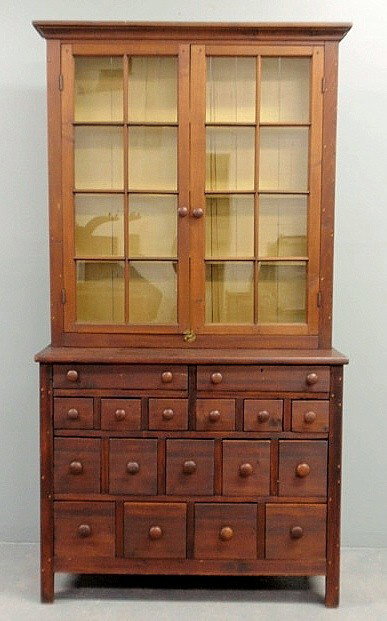 Pine two-piece apothecary cabinet, c.1830, the up: Pine two-piece apothecary cabinet, c.1830, the upper section with a molded cornice over two six-light doors above a lower section with multiple drawers. 83"h.x43"w.x16.25"d.