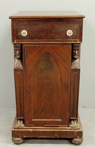 Empire mahogany cabinet in the manner of Joseph B: Empire mahogany cabinet in the manner of Joseph Barry, Philadelphia, with a single drawer above an arched paneled door flanked by carved caryatids and ending in ball feet. 44.5"h.x23"w.x27"d.