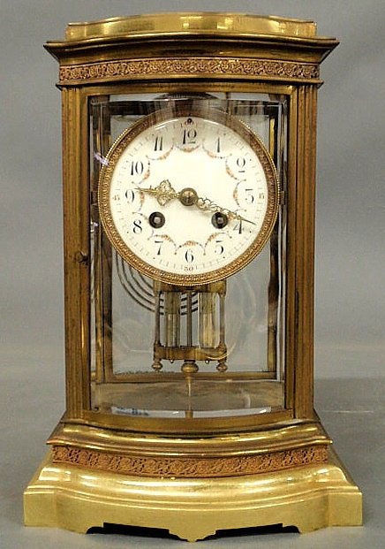 French brass mantel clock with beveled glass, a p: French brass mantel clock with beveled glass, a porcelain face with Arabic numerals and a mercury pendulum. 12”h.x8”w.x7”d. Note: this item cannot be shipped due to mercury content.