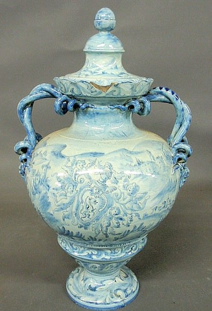 Massive blue and white Italian faience covered ur: Massive blue and white Italian faience covered urn, 19th c., decorated with masks, figures, goats and cherubs and with snake handles. As found. 25”h.x15”w.