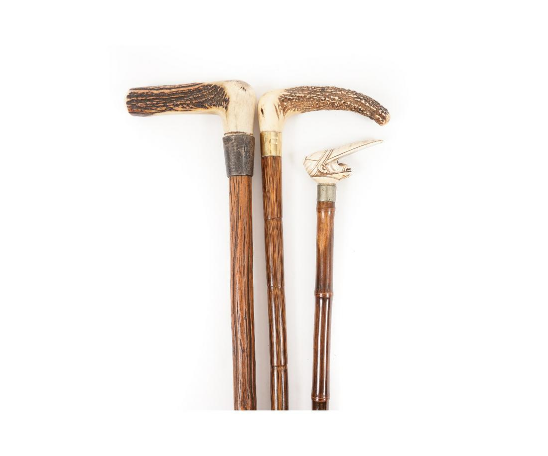 STAG HANDLED WALKING STICKS: Two stag handled walking sticks one with 14k gold band; together with a carved bone monkey jockey. Monkey Jockey: 35"l x 3.5"w