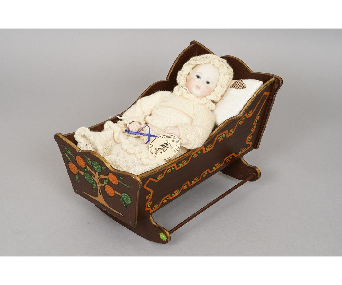 ROCHE NEW BABY DOLL: "New Baby and Cradle" artist doll by Lynn & Michael Roche, limited edition #15/50 dated 1989, original tag, porcelain head, arms, legs and cloth body. New Baby is dressed in a hand knit ruffled baby g