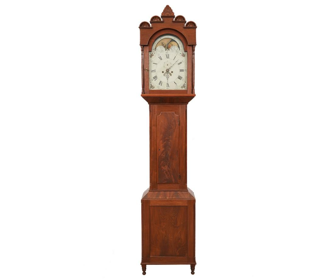 EARLY SHERATON TALL CASE CLOCK: American Sheraton mahogany tall case clock, circa 1825, possibly Lancaster, OH or PA, with unusual carved bonnet, 8-day works with alarm, moon dial, calendar and Roman numerals, the case with shaped c