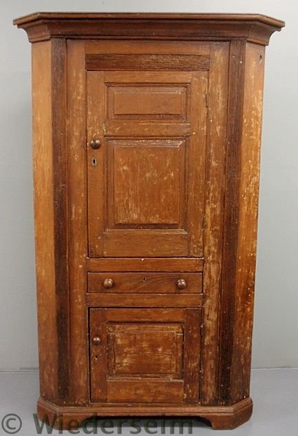 Pine one-piece corner cupboard, early 19th c., wi: Pine one-piece corner cupboard, early 19th c., with a molded cornice over a paneled door, single drawer and lower paneled door all on straight bracket feet. 78”h.x46”w.