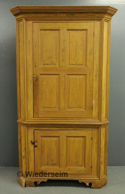 Two-piece corner cupboard with yellow paint decora: Two-piece corner cupboard with yellow paint decoration, 19th c, with a molded cornice above a raised panel door, all above a conforming base. 88"h.x49"w.x22"d.