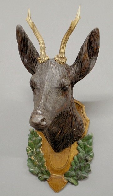 Black Forest carved stag head, late 19th c., with glass: Black Forest carved stag head, late 19th c., with glass eyes and mounted on an oak leaf and acorn carved plaque. 24”h.x10.5”w.x11”d.