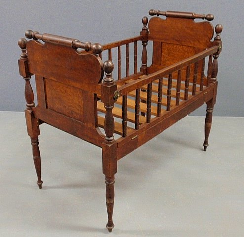 Sheraton cherry and bird’s-eye maple crib with rolling: Sheraton cherry and bird’s-eye maple crib with rolling in turned head and foot boards and drop side. 40”h.x25.5”w.x46.5”l.