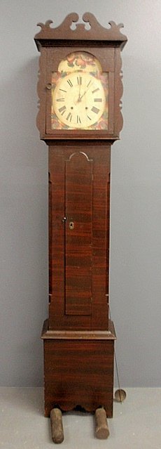 Grain paint decorated tall case clock, c.1850, probably: Grain paint decorated tall case clock, c.1850, probably German, with a scrolled crest above a white painted wooden dial with red, blue and green floral decoration above an arched door flanked by chamf
