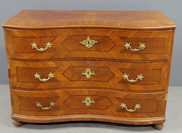 Biedermeier fruitwood veneered and inlaid serpentine: Biedermeier fruitwood veneered and inlaid serpentine front three-drawer chest, early 19th c., with fire gilt brass handles. 34"h.x49"w.