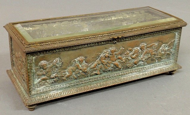 Continental metal casket-form storage box, c.1820, with: Continental metal casket-form storage box, c.1820, with raised relief putti decoration and the lid with inset glass with etched floral decoration. 4.5"h.x11.25"w.x4"d.