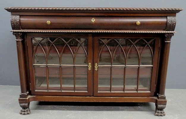 Chippendale style mahogany sideboard, c.1920, with one: Chippendale style mahogany sideboard, c.1920, with one long drawer above two gothic mullioned glass doors opening to pull-out drawers and all resting on animal paw feet. 37"h.x54"w.x22"d.