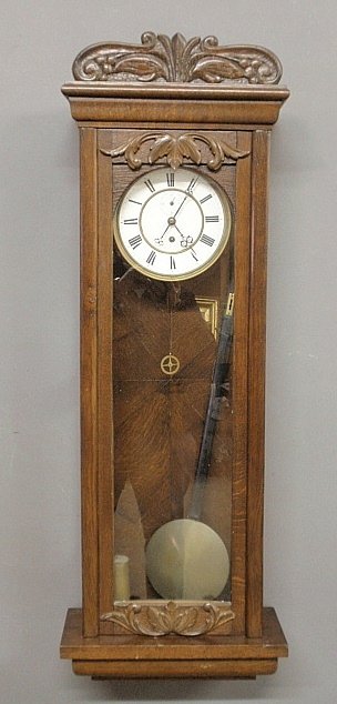 German oak cased wall clock, c.1900, with a porcelain: German oak cased wall clock, c.1900, with a porcelain dial and brass weight. 39"h.x13"w.x6"d.