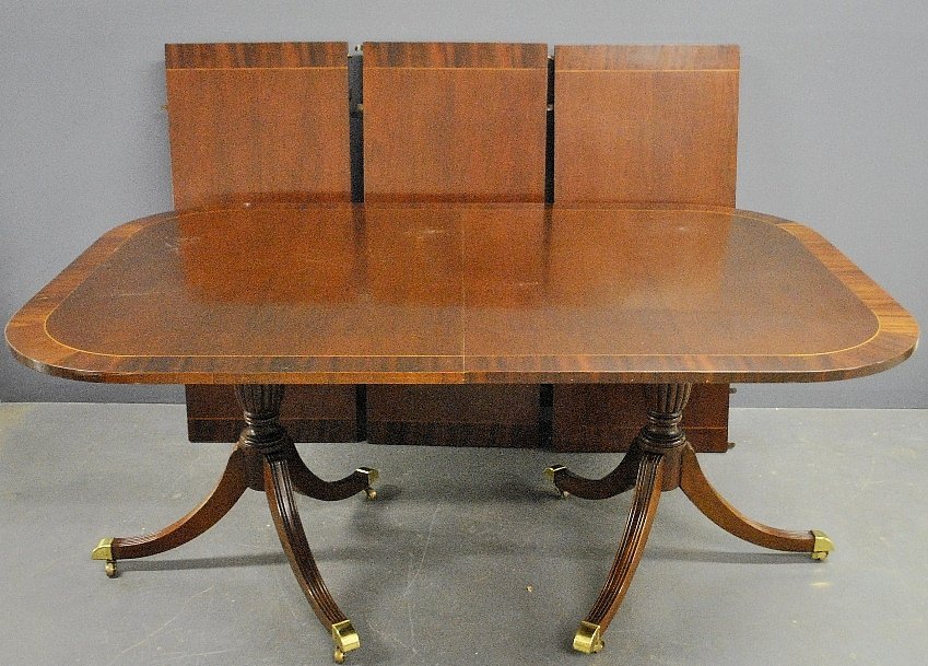 Duncan Phyfe style mahogany banquet table by Baker: Duncan Phyfe style mahogany banquet table by Baker Furniture with a banded edge, double pedestal base and brass casters and 3 extra leaves. 31"h.x45"w.x63"l., each leaf 20"