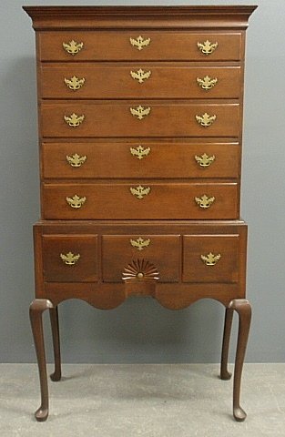New England Queen Anne cherry highboy, c.1770, with a: New England Queen Anne cherry highboy, c.1770, with a molded cornice above five graduated drawers over a lower section with a shell carved center drawer, cabriole legs and disc feet. Provenance: Ginsb