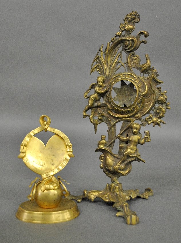 Gilt metal soldier's watch safe decorated with cannon: Gilt metal soldier's watch safe decorated with cannon ball and stirrups 5.5"h., late 19th c., and a French brass example with cherubs,12.25"h