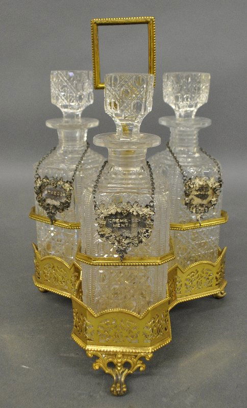 English gold wash over plate decanter stand with three: English gold wash over plate decanter stand with three cut glass bottles each with English silver wine labels. 13"h.x9"dia.