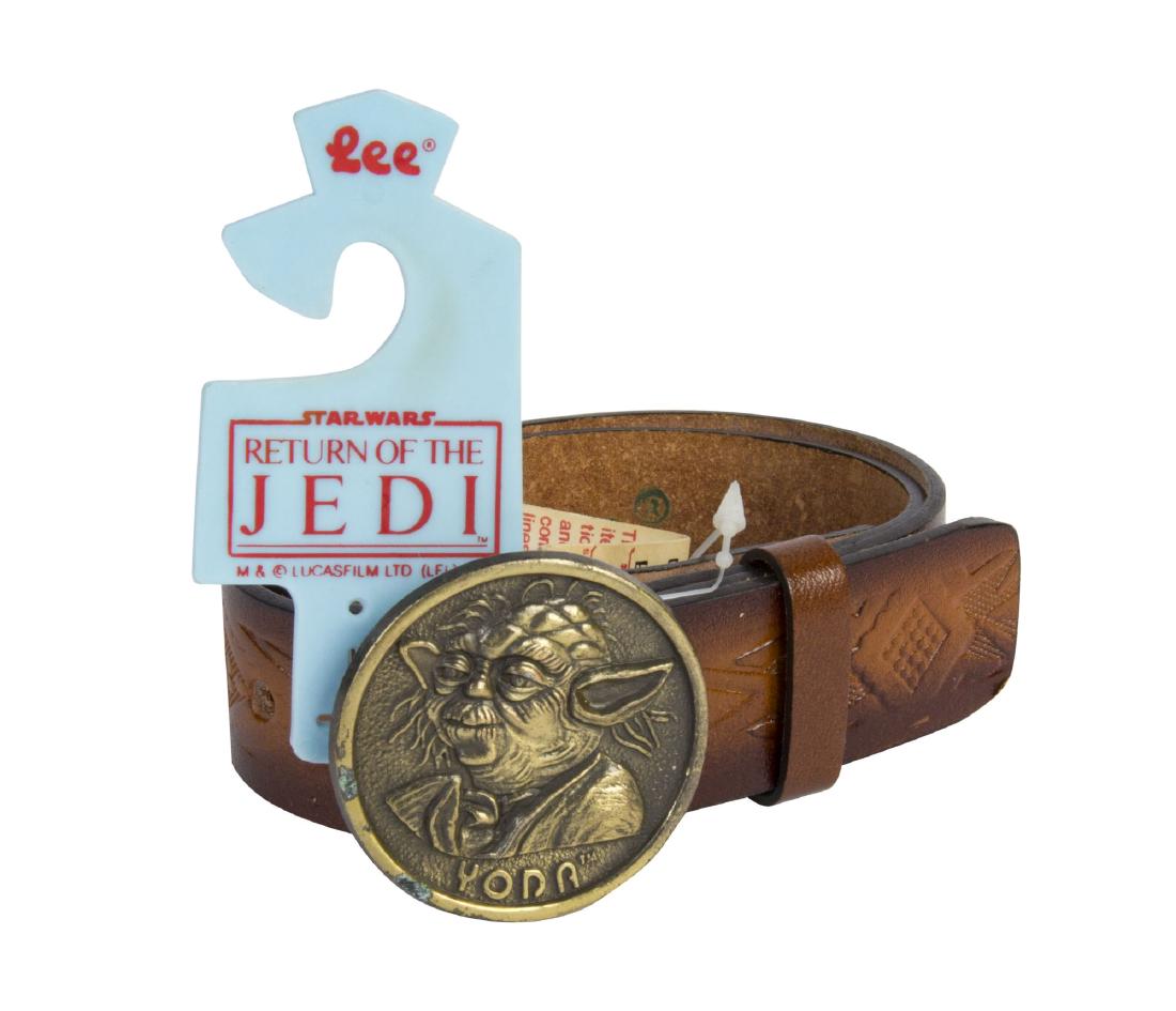 "Return of the Jedi" Yoda Brass Belt.: (LucasFilm, 1982) An unused leather belt with a brass Yoda buckle from "Return of the Jedi". The belt is unused with its original tag from Marshalls, and was created by Lee Belt Co. Still coiled as or