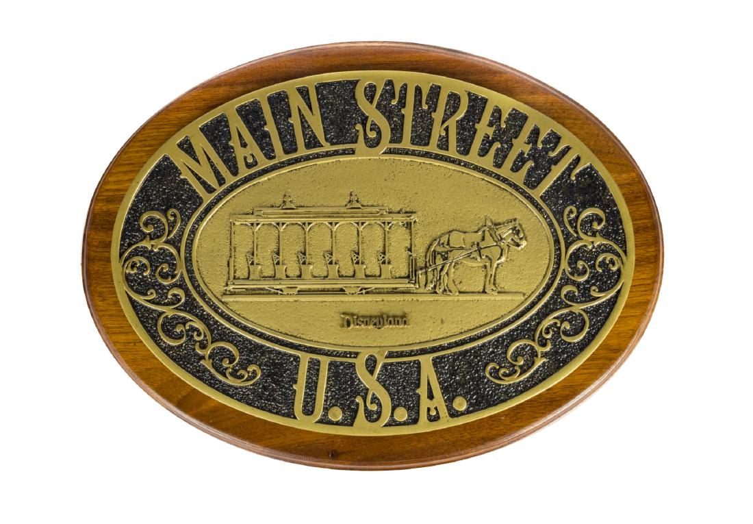 Disneyland Main Street Trash Can Plaque Replica.: (Disneyland, c.2000s) A beautiful replica plaque that faithfully recreates the similar plaques seen on the trash can of Main Street. Reading "Main Street U.S.A.", this resin plaque depicts on of the h
