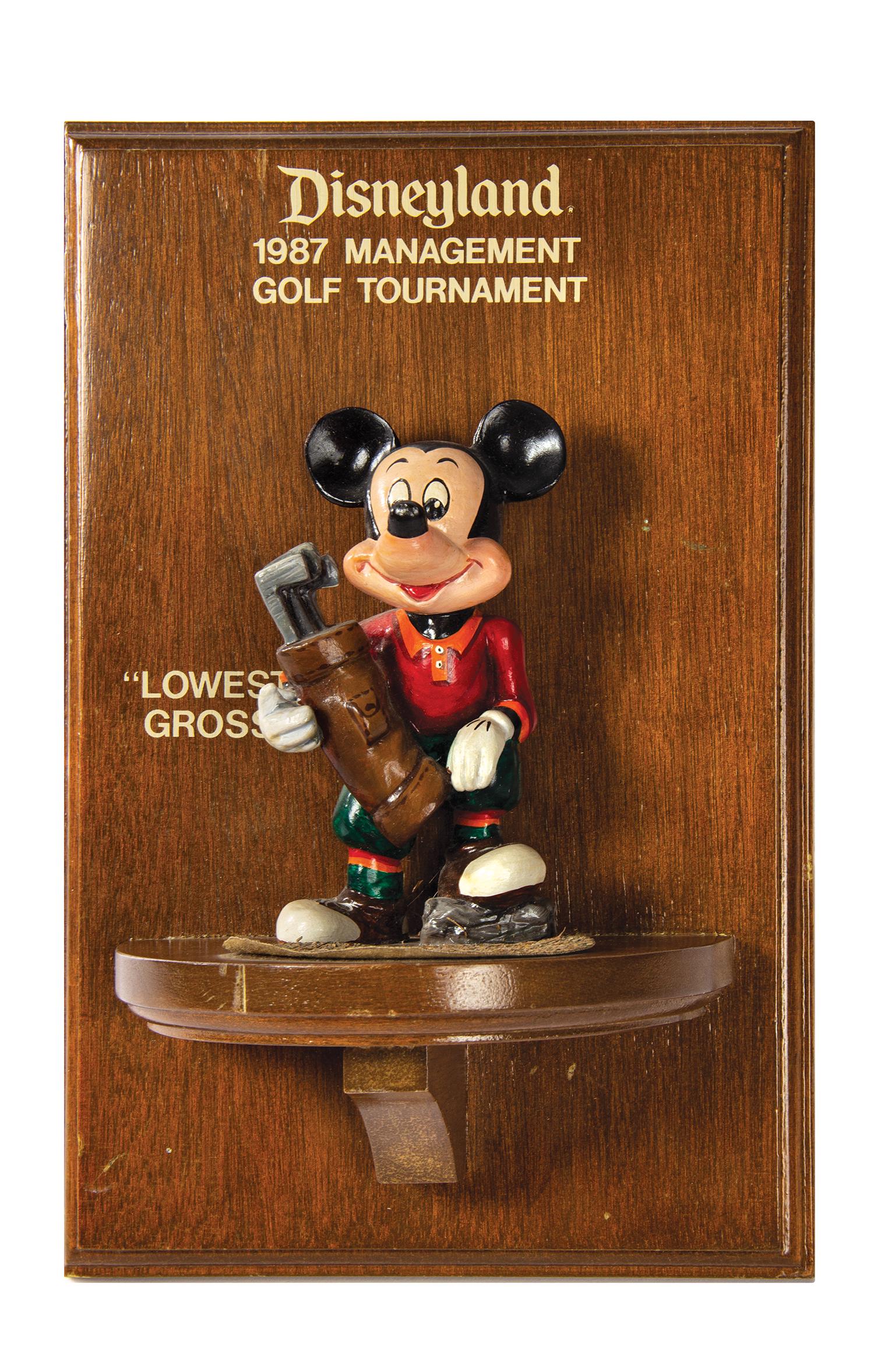 Disneyland Management Golf Tournament Award.: (Disneyland, 1987) A very rare award given as part of a golf tournament for the park's management in 1987. The award features a golfing Mickey Mouse on a wooden plaque, in recognition of "Lowest Gross