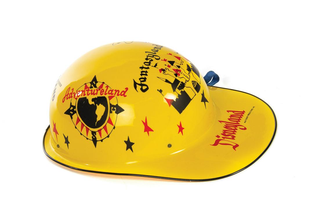 Yellow Souvenir Keppy Kap.: (Disneyland, 1950s) A souvenir yellow "Keppy Kap" featuring artwork of the different lands of the park. The original manufacturer's sticker is still attached to the inside of the cap's dome. Measuring