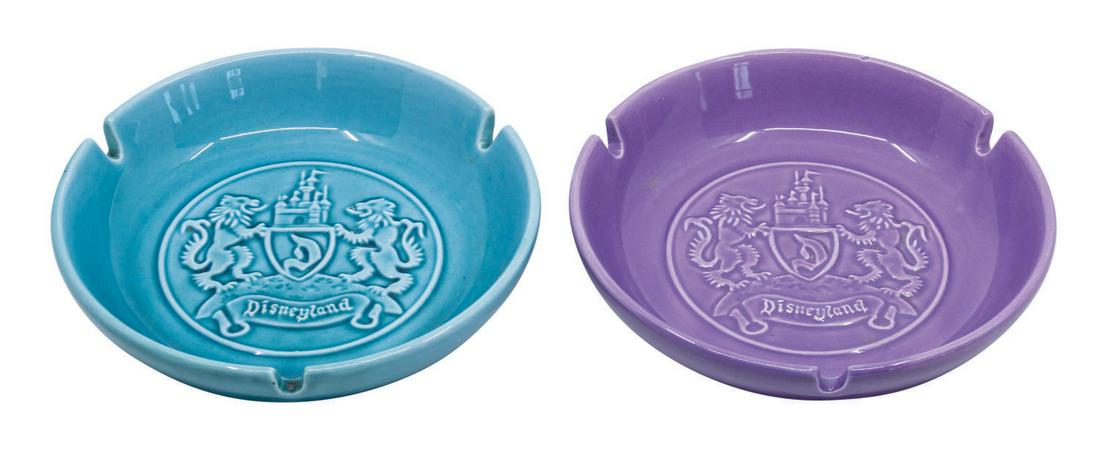Pair of Disneyland Crest Ashtrays.: (Disneyland, c.1950s) A pair of early souvenir ashtrays from Disneyland. The ceramic ashtrays feature a Disneyland crest in relief at the center of the bowl. Each retains a Disneyland Walt Disney Prod