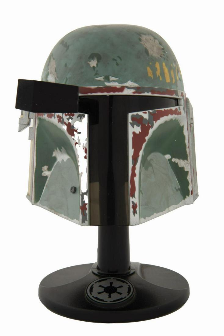 A Miniature Boba Fett Helmet by Riddell.: (Lucasfilm/Riddell, 1997) A Miniature Boba Fett Helmet, produced by Riddell. The helmet is realized at 45% of actual size and patterned after the screen-used original. Constructed with diecast metal p