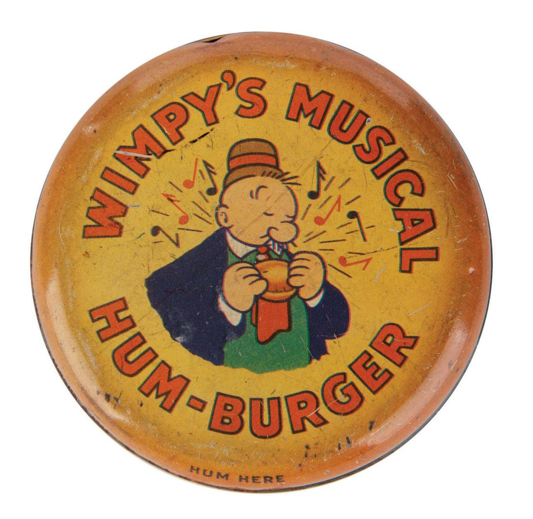 A "Wimpy's Musical Hum-Burger" Tin Litho Toy.: (Northwestern Products, 1936) A tin litho "Wimpy's Musical Hum-burger" toy. Designed to look like Wimpy's favorite food, the hamburger, it features an image of Wimpy on one side while the reverse has 