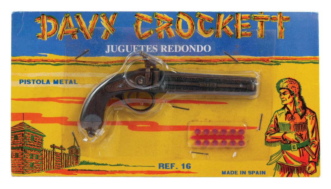 A Davy Crockett Cap Gun.: (1950s) A Davy Crockett cap gun, manufactured in Spain. The metal replica of a flintlock is sealed on its unopened card, with (12) original caps. Measuring 6" on the 9.5"x5" card, the piece is in fine