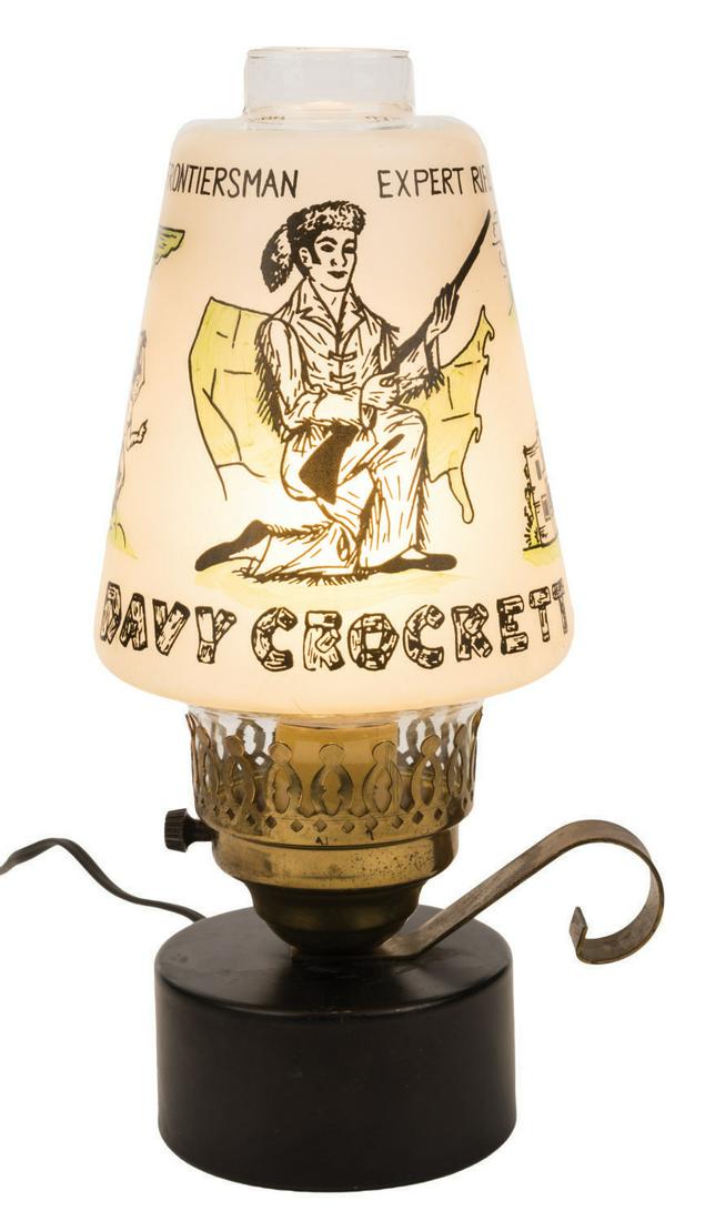 A Davy Crockett Brass and Glass Electric Lamp.: (1950's) A Davy Crockett lamp styled to look like an old-fashioned gas lamp. The hurricane glass style top illustrates great moments in Crockett's life. Measuring 5" at widest diameter and 12" high, t