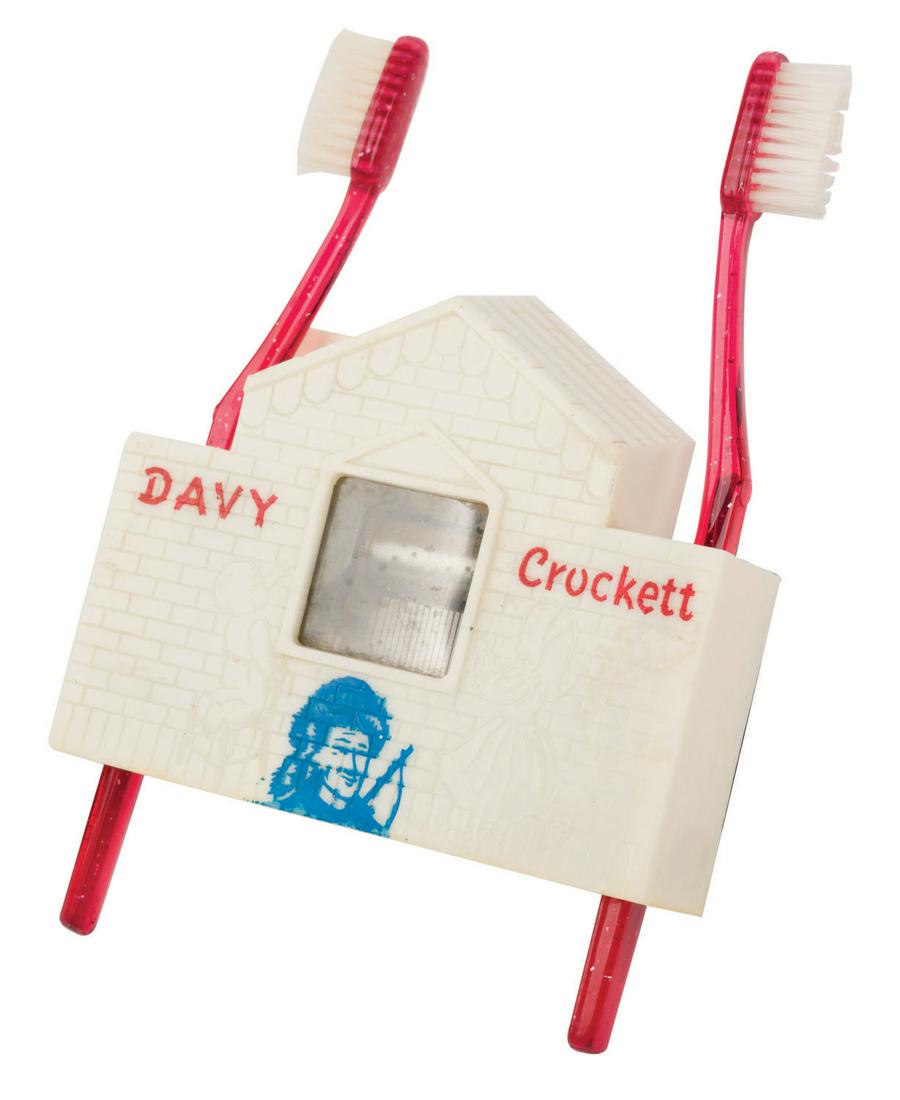 A Davy Crockett Musical Toothbrush Holder by Wal-Feld.: (Wal-Feld, 1950s) A Davy Crockett Musical Toothbrush Holder by the Wal-Feld Company. The plastic two-toothbrush holder features imagery of Davy Crockett on the face, a visible music box with pull cord
