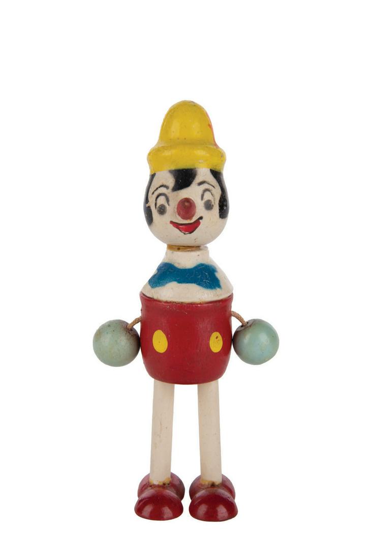 A Pinocchio Wooden Figure.: (George Borgfelt Co., 1940s) A Wooden figure of Pinocchio with cord arms distributed by the George Borgfeldt Co. Standing 4.75" tall, the figure is in very good condition with light wear and loose cor