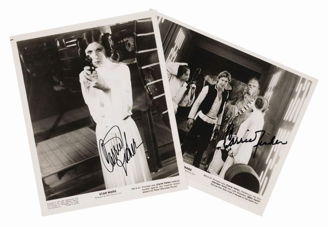 A Pair of Carrie Fisher Signed Star Wars Photos.: (20th Century Fox, 1977) A pair of “Star Wars” publicity photos signed by Carrie Fisher in black marker. One photo features Fisher as Princess Leia pointing a gun at the camera, while the othe