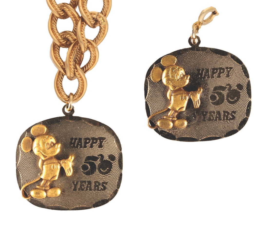 A Walt Disney Productions 50th Pendant and Bracelet.: (Disneyland, 1973) A bracelet and pendant commemorating the 50th anniversary of Walt Disney Productions. The bracelet measures 5" in length and the pendant is 1" in diameter. Both pieces are in fine c