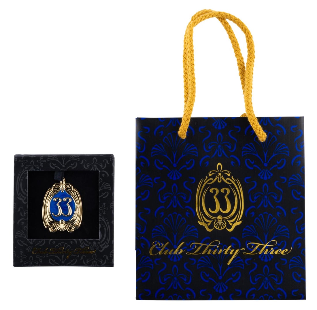 A Club 33 Updated Logo Pin and Bag.: (Disneyland, 2023) A limited-release Club 33 pin featuring the exclusive dining location’s updated logo. The lot also includes a 6” x 6.5” Club 33 gift bag. Measuring 1.5” x 2&rdqu
