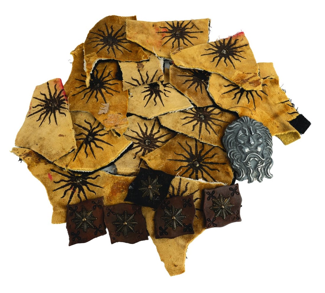 A "Game of Thrones" Lannister Prop and Costume Swatches.: (HBO, 2011-2019) A "Game of Thrones" House Lannister lion armor prop and 15 swatches for the Dornish Guard uniforms, protectors of House Martell. 13 of the swatches are well-maintained, while 2 are in