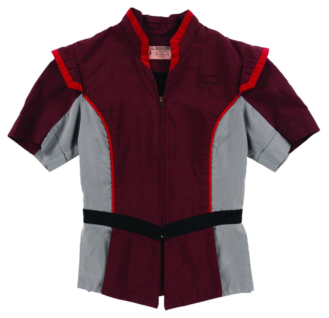 A Tomorrowland Outdoor Vending Host Shirt: (Walt Disney World, 2000s) A shirt worn by Tomorrowland Outdoor Vending Hosts at the Magic Kingdom. Labeled a size female XS, the shirt is in good condition with pilling, discoloration from age, and w