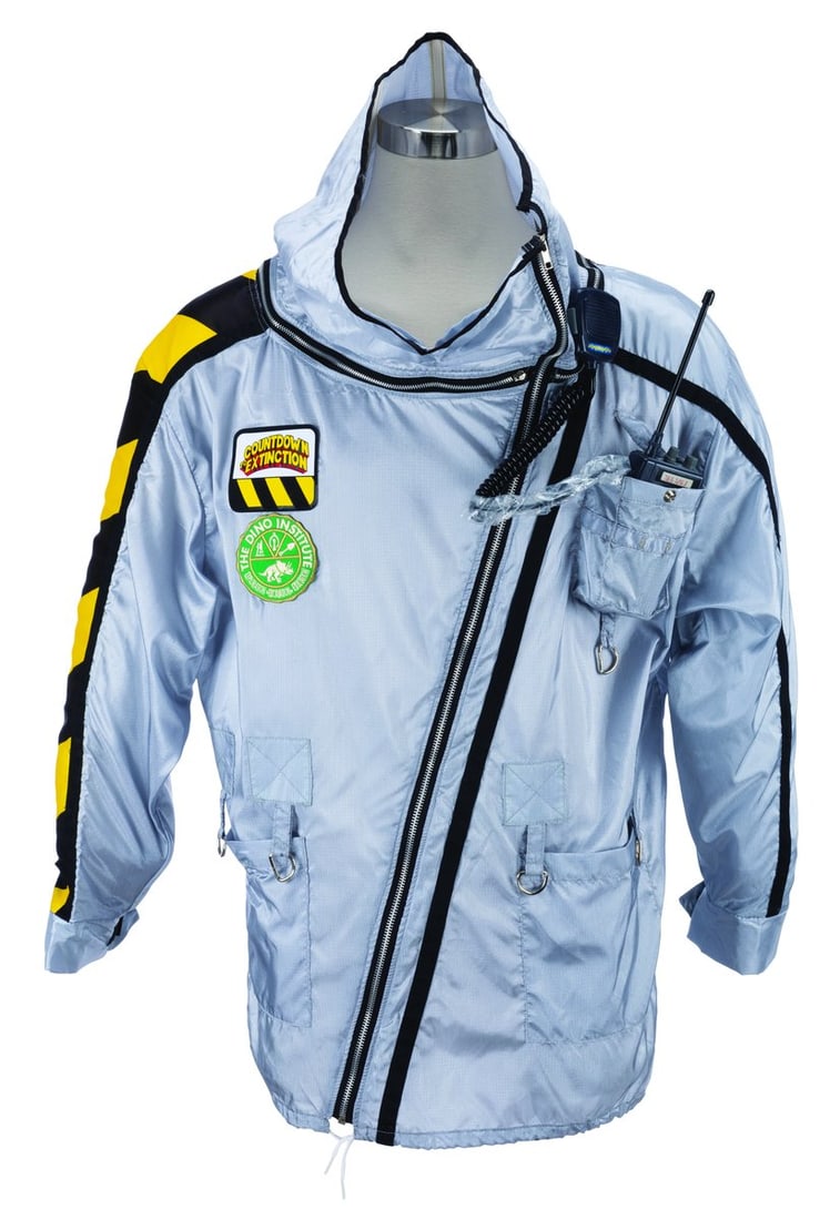 A Countdown to Extinction Cast Member Jacket.: (Disney's Animal Kingdom, 1998-2000) A rare silver Cast Member costume jacket featuring a Countdown to Extinction patch, Dino Institute patch, and a prop walkie-talkie. Due to the black and yellow saf