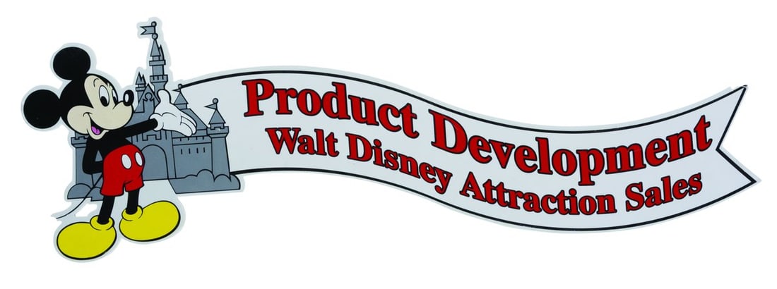 A Walt Disney Attraction Sales Product Development Sign.: (Disneyland, 2000s) A Walt Disney Attraction Sales Product Development sign featuring Mickey Mouse and Sleeping Beauty Castle. Measuring 8.5" x 25", the sign is in good condition, with scratches, scuf